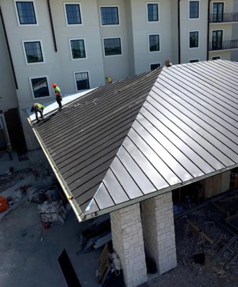 Crew installing standing seam metal roof panels on a commercial project in Middleburg